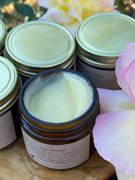 Jar of cream with a visible label, surrounded by flowers on a wooden surface