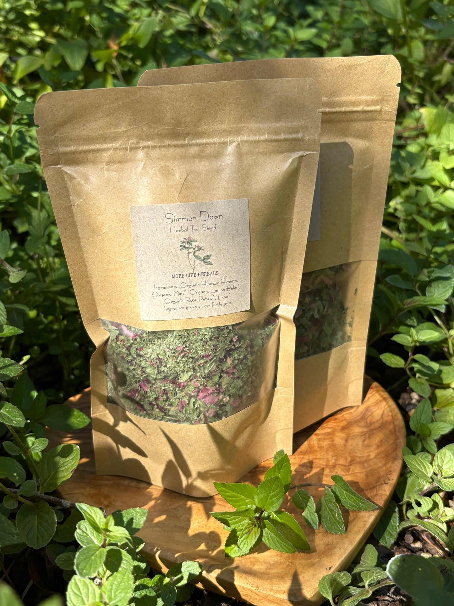 Kraft paper bag with tea leaves and a label on a wooden board with fresh mint in the background