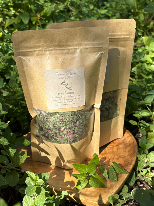 Kraft paper bag with tea leaves and a label on a wooden board with fresh mint in the background