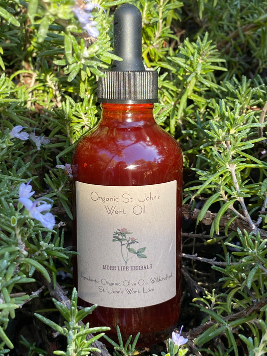 A bottle of Organic St. John's Wort Oil with a dropper, labeled with the product name and a brief description, set against a natural background with greenery.